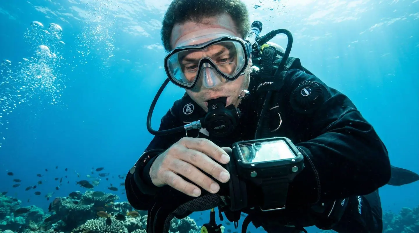 Plongeur en apesanteur sous l'eau consultant son ordinateur de plongée avec un masque bifocal correcteur